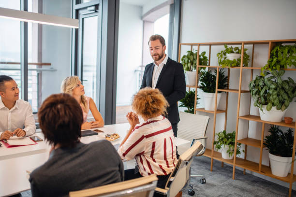 Young Businessman Answering Question during Presentation Side view close-up of smiling businessman in early 20s responding to question during presentation in corporate board room. men close up 20s asian ethnicity stock pictures, royalty-free photos & images