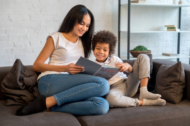 istock Happy pretty mother holding book with her little son 1202521889