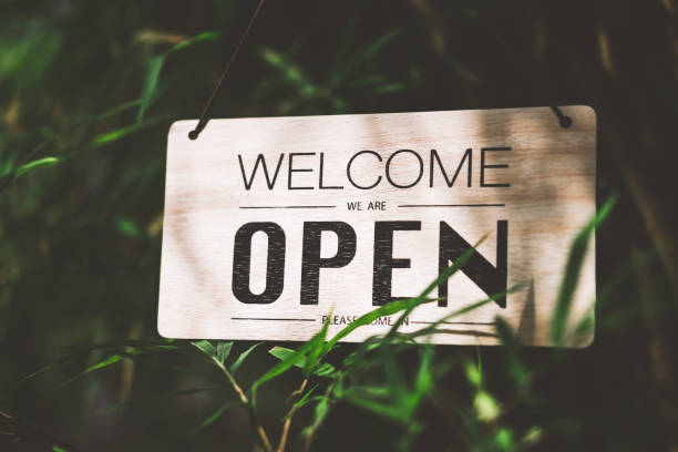 istock Wooden open sign hanging on bamboo tree with green nature bokeh sunlight background. 1202522401