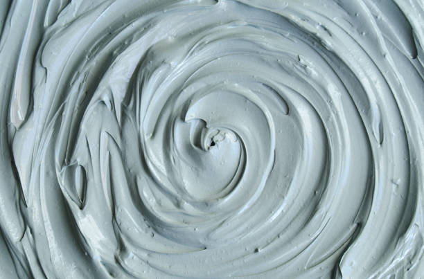 Gray bentonite facial clay (mask, face cream, body wrap) texture close up, selective focus. Abstract background with circle brush strokes.