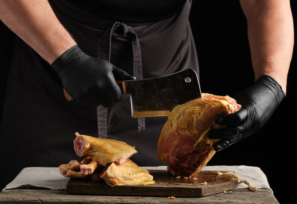 istock chef in black uniform and latex gloves chopping raw chicken into pieces 1202523794