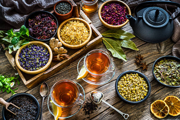 허브 차: 소박한 나무 테이블에서 위에서 촬영한 다양한 말린 차 잎과 꽃이 있는 차 2잔 - herbal tea 이미지 뉴스 사진 이미지