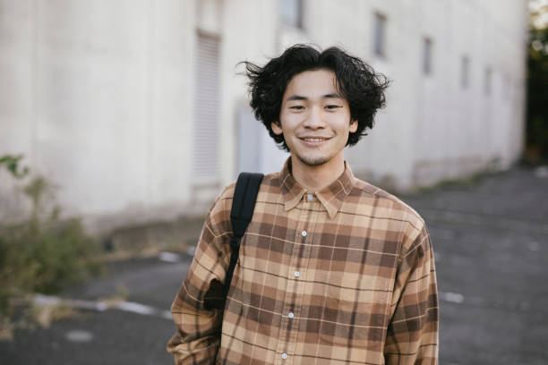 Portrait of Young Asian Man Smiling Asian man with long hair looking at camera. alternative lifestyle photos stock pictures, royalty-free photos & images