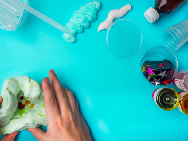 istock Components to make slime. Child education concept. On blue surface slime, toothpaste, shaving foam, decorative accessories, color paints on blue background 1202530495