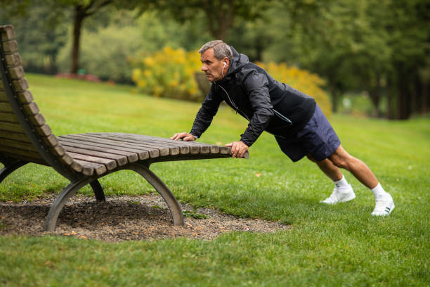 Mature man doing push-ups on bench in public park