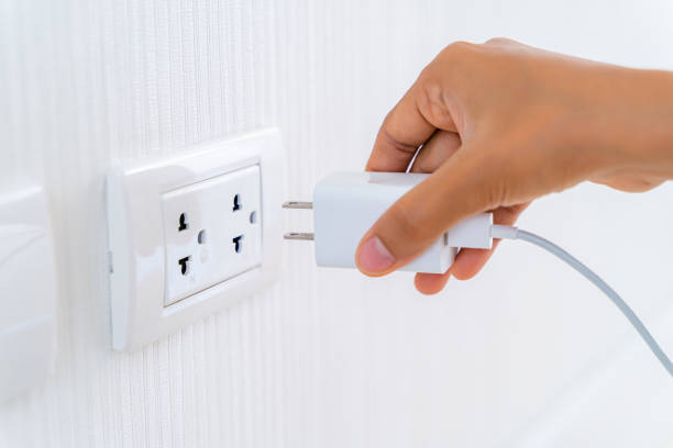 壁のコンセントのコンセントに電気電源コードプラグを挿入する女性の手。 - electric plug outlet pulling electricity ストックフォトと画像