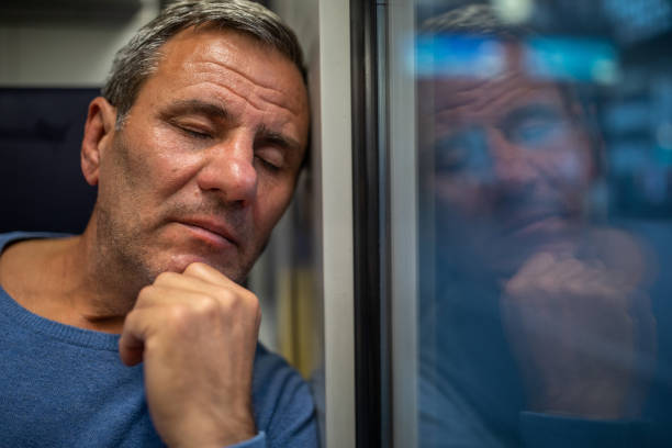istock Tired mature man taking a nap while traveling in train 1202530898