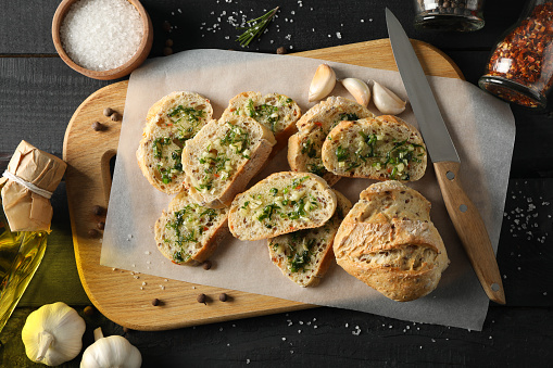 Board of toasted garlic bread on wooden background, top view