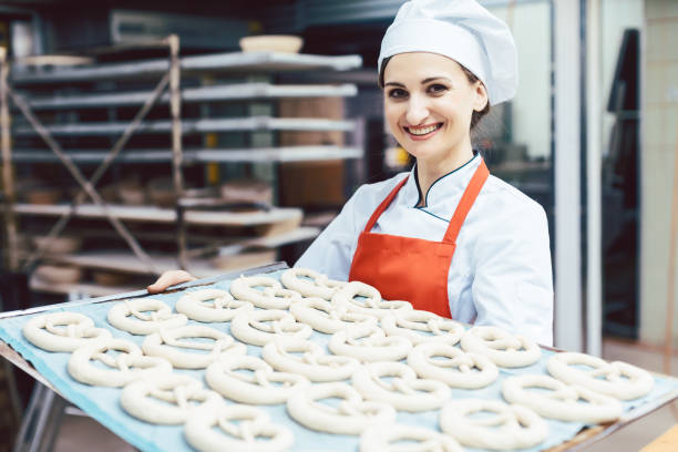 istock Baker showing sheet with bread ready to be baked 1202532157