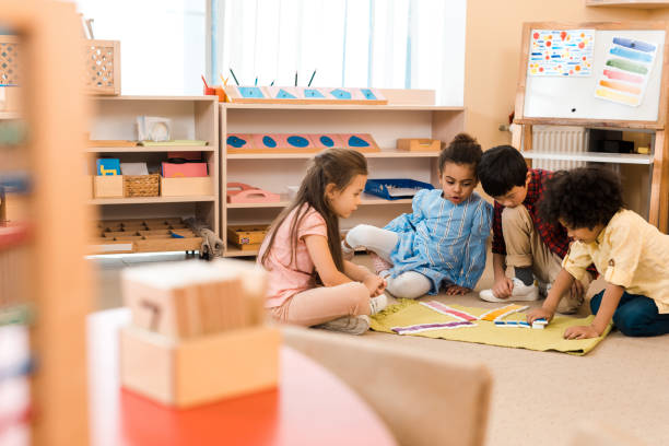 Selective focus of children playing game on floor in montessori school Selective focus of children playing game on floor in montessori school montessori education stock pictures, royalty-free photos & images