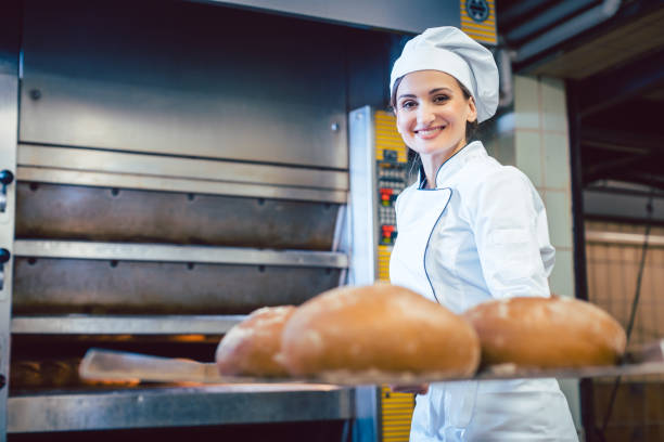 istock Baker woman showing freshly baked bread on shovel 1202532436