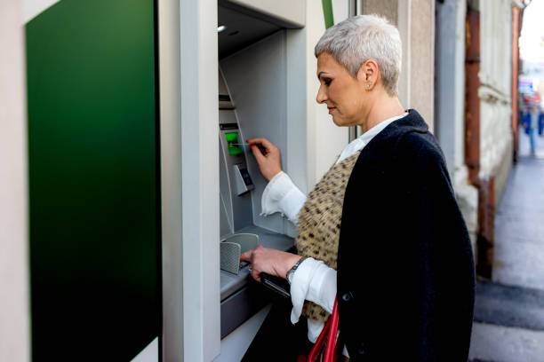 istock Middle age woman is withdrawing money from ATM machine 1202534835