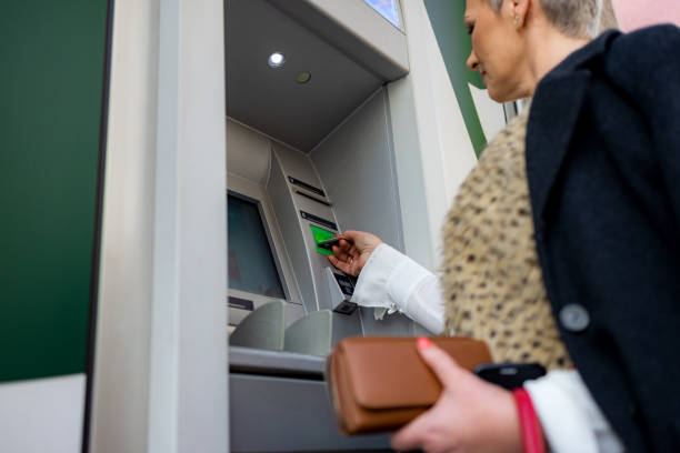 istock Middle age woman is withdrawing money from ATM machine 1202535787