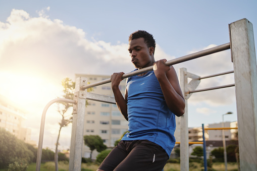 Young african american man doing pull-ups exercise at the gym park