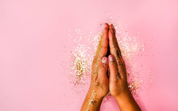 istock Woman's hands and golden glitters on pink background. Festive flat lay concept. 1202537175