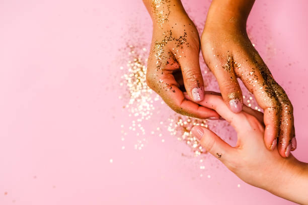 istock Woman's hands and golden glitters on pink background. Festive flat lay concept. 1202537209