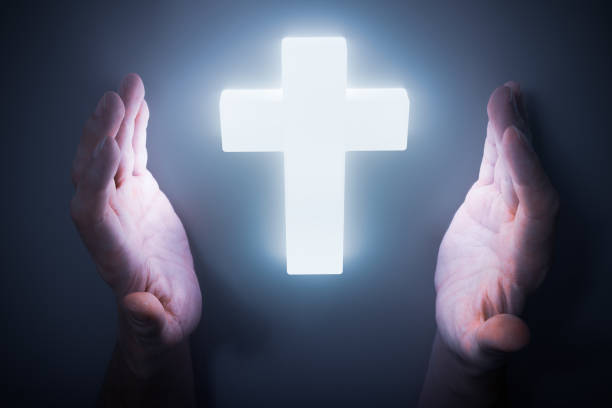 istock Man hands around shining light from glowing crucifix. Religion concept. 1202538124