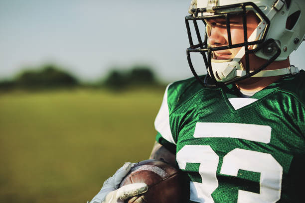istock Football quarterback holding a ball during a team practice 1202538241