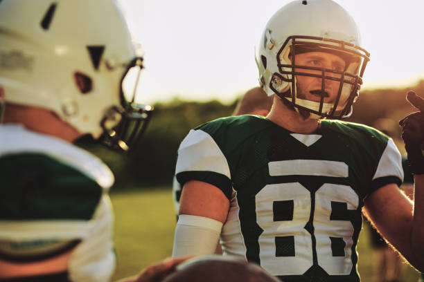 istock Football quarterback talking with his team during practice 1202538315