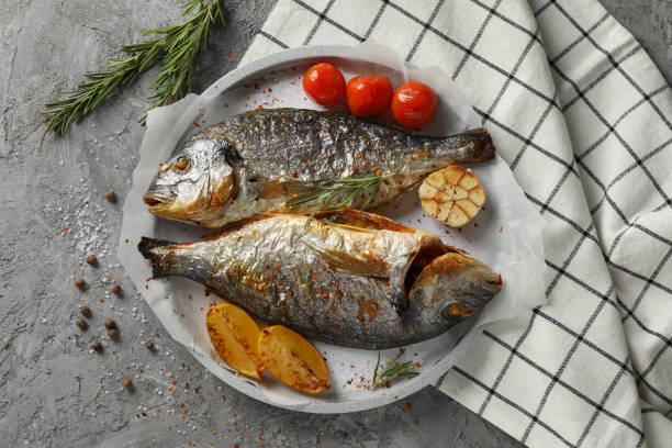 istock Plate with baked Dorado on garnished grey background, top view 1202538630