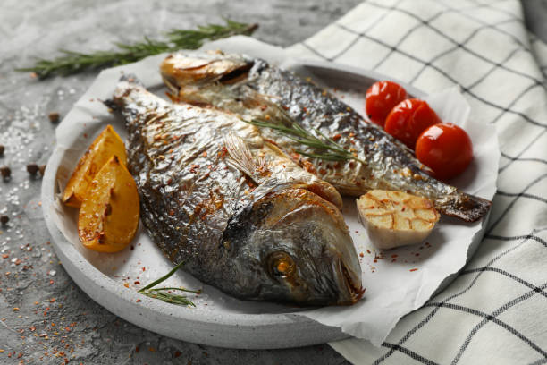 istock Plate with baked Dorado on garnished grey background, close up 1202539075