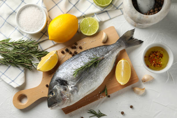 istock Cutting board with Dorado fish and cooking ingredients on white background, top view 1202539895