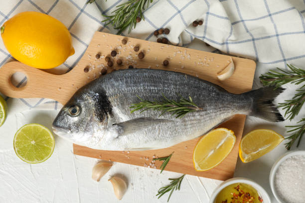 istock Cutting board with Dorado fish and cooking ingredients on white background, top view 1202539998