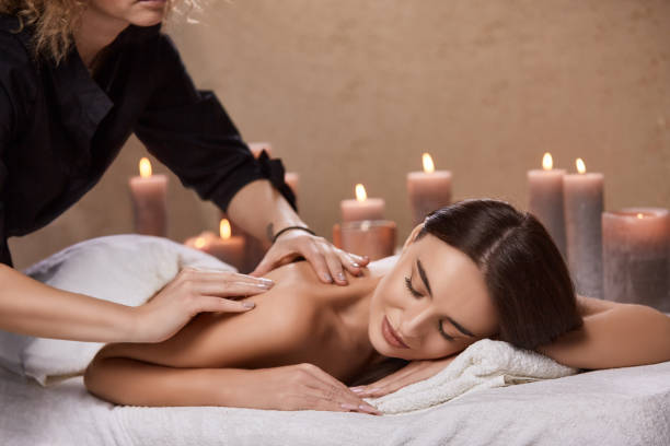 istock masseur doing massage for woman's back in spa salon with many candles 1202540444