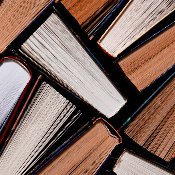 istock Lots of colourful thick open books stand on a dark background 1202541746