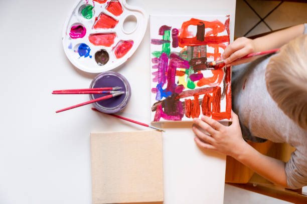istock Little boy painting with brushes Top View 1202542055