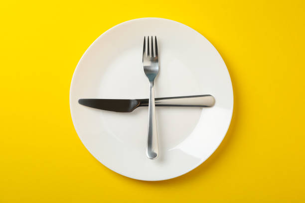 istock Plate with fork and knife on yellow background, top view 1202543189