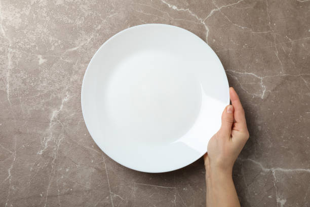 istock Female hand hold plate on grey background, top view 1202543736