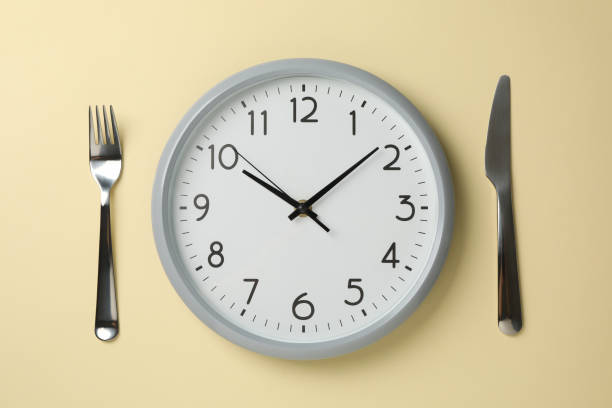 istock Clock, knife and fork on beige background, top view 1202544753