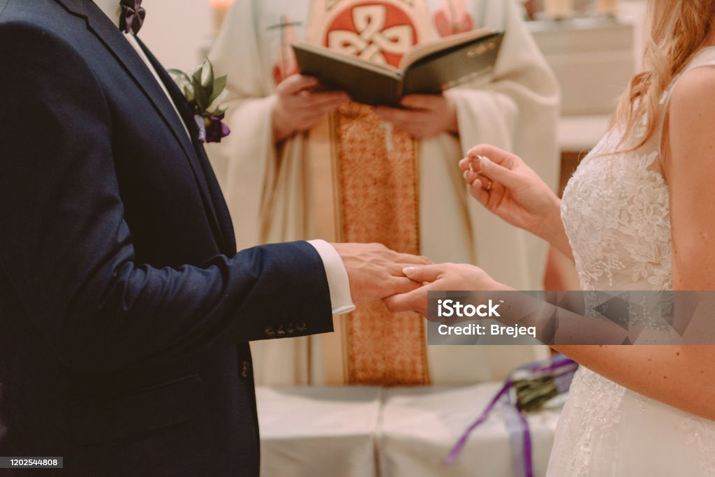 the bride and groom during the wedding ceremony put wedding rings on their fingers the bride and groom during the wedding ceremony put wedding rings on their fingers. Church Stock Photo