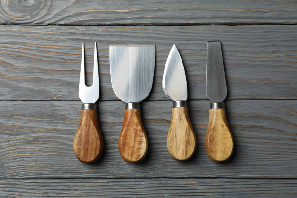 istock Cheese knives on wooden background, top view and space for text 1202544860