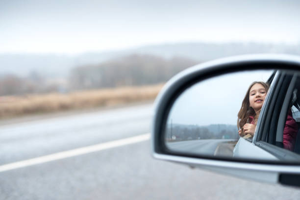 istock Young girl ride car and look out open window 1202545038
