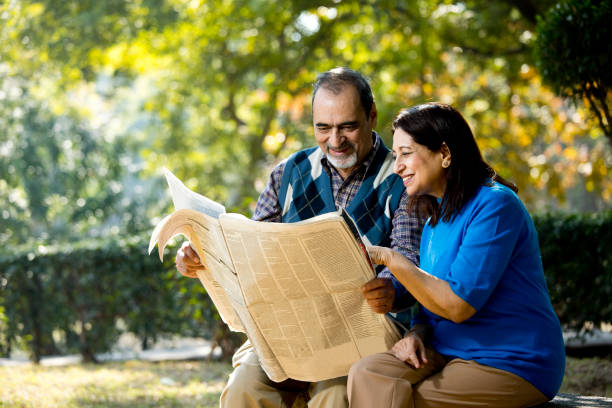 istock Happy senior couple reading newspaper outdoors at park 1202545068