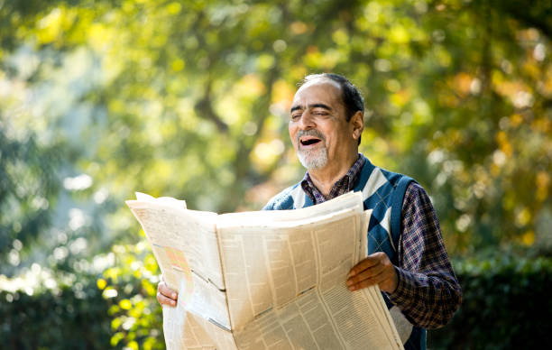 istock Senior man reading newspaper in the park 1202545175