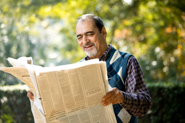istock Senior man reading newspaper in the park 1202545561