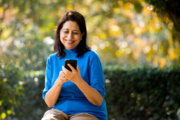 happy senior woman text messaging using mobile phone - mobile phone text messaging people asian ethnicity imagens e fotografias de stock