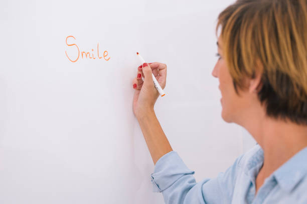 istock Female teacher writing on a whiteboard the word smile. 1202548541