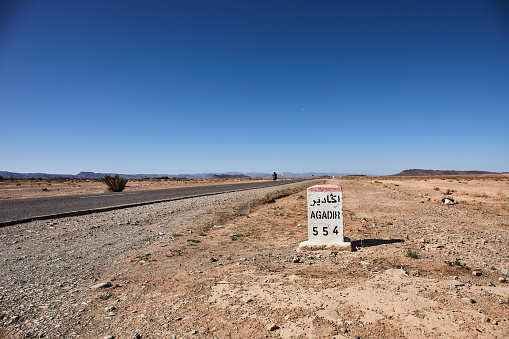 Road to Agadir. Milestone indicating Agadir in a desertic area of Morocco