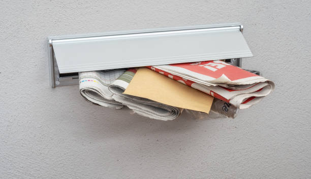 istock Newspapers and a letter in a mail slot 1202550059