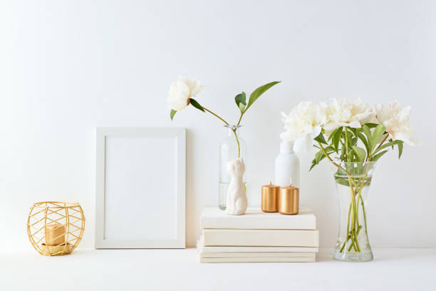 Home interior with decor elements. White frame, white peonies in a vase, interior decoration Home interior with decor elements. White frame, white peonies in a vase, interior decoration candlelight photos stock pictures, royalty-free photos & images