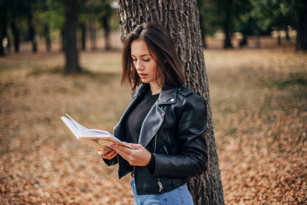 istock Beautiful young woman is reading a book 1202550637