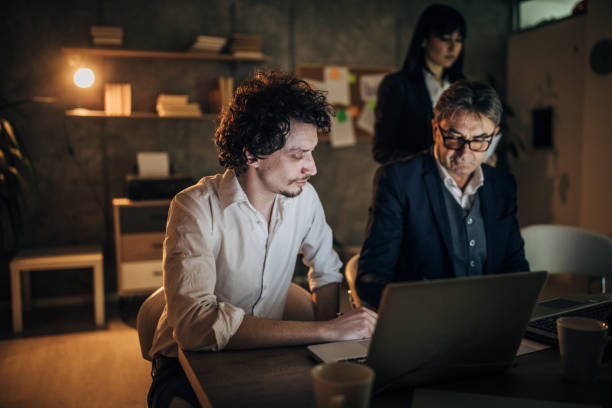 istock Three colleagues working late at night in office together 1202552049