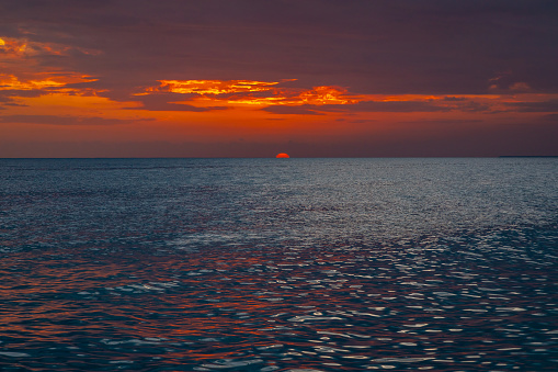 Beautiful sunset on the Caribbean, bright orange sun in the clouds.