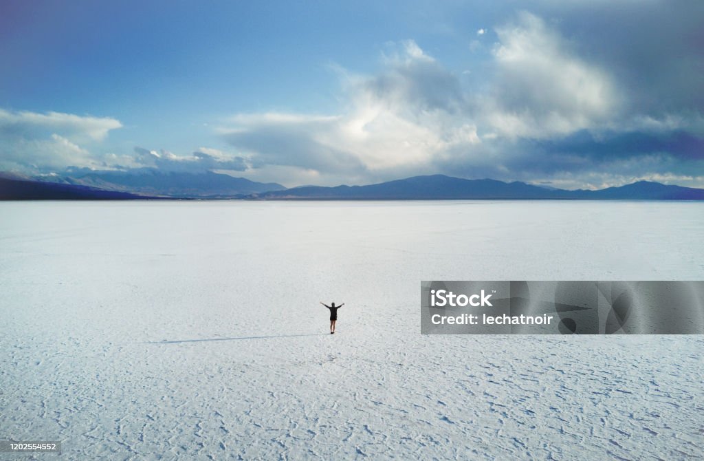 Woman in the middle of the salt desert - aerial view A scenic view from above on a lone woman standing in the middle of the salt desert in Salta, Argentina. Humahuaca Stock Photo