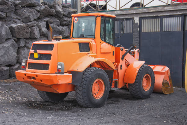 istock An orange tractor with a bucket in front is parked in the mountains. 1202555197