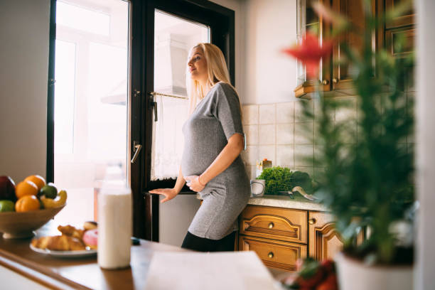 istock Pregnant woman waiting and looking through window 1202555815